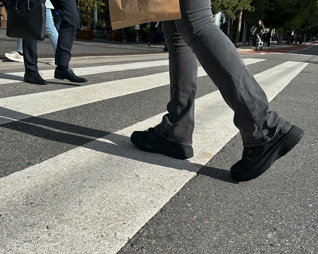 Person with black GaitLine shoes walking across a road